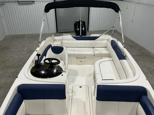 Slide: The Image of 2016 Bayliner 190 Deck Boat with blue and white seating in a storage facility. - 9