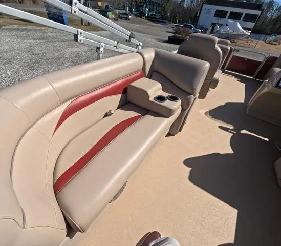 Slide: The Image of 2015 Sweetwater SW 2286 SLC boat interior with beige and red seating, cup holders, and open deck. - 13