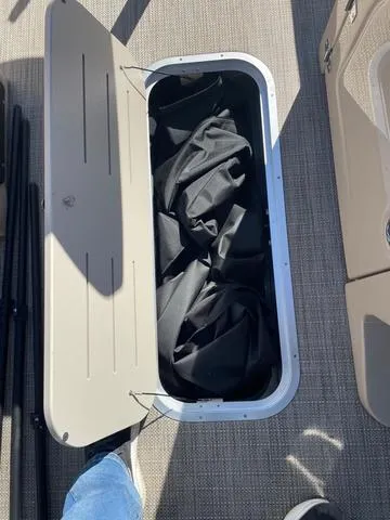 Slide: The Image of Storage compartment on 2025 Bentley Pontoons 223 Legacy Swingback, open with black fabric inside. - 12