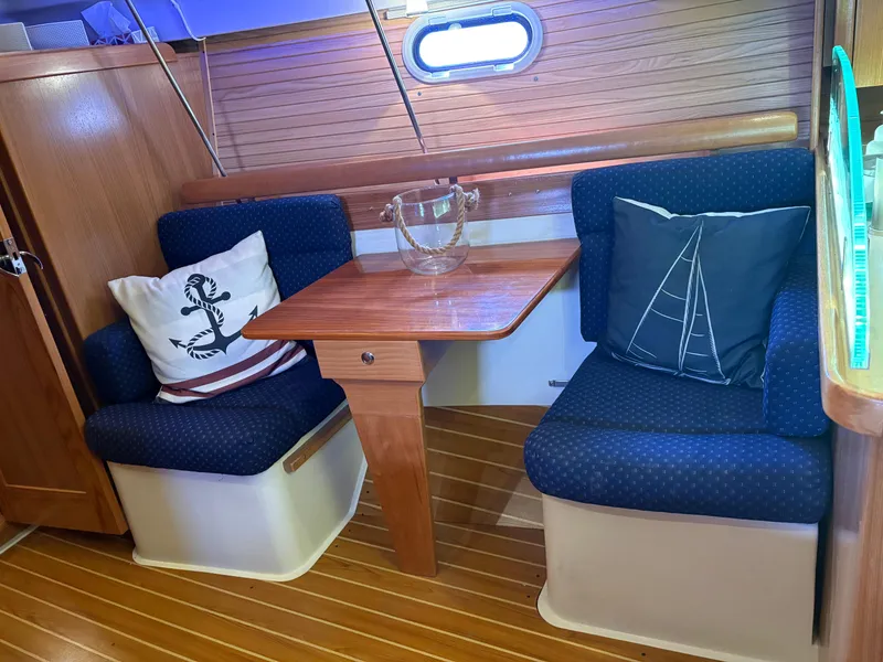 Slide: The Image of Cozy interior of 2010 Catalina 350 sailboat with wooden table and nautical-themed cushions. - 23