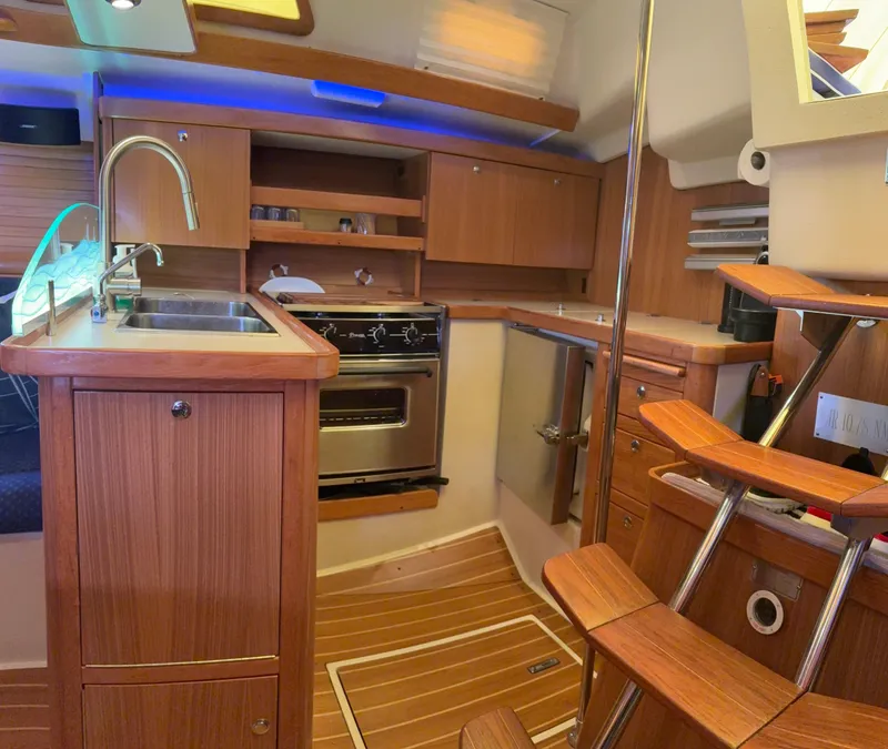 Slide: The Image of Interior of a 2010 Catalina 350 sailboat with wooden cabinetry and modern kitchen amenities. - 25