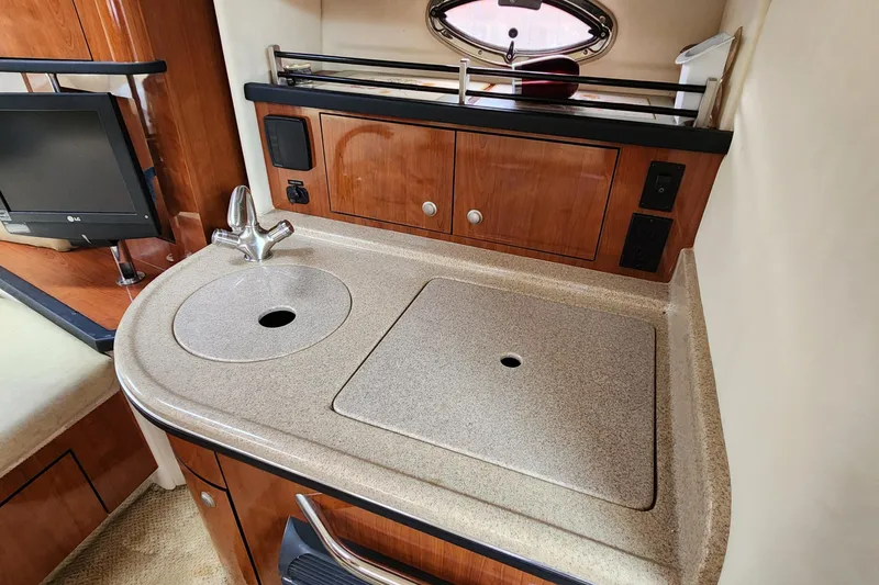 Slide: The Image of 2007 Sea Ray 290 Sundancer galley with sink, countertop, and wooden cabinetry. - 10