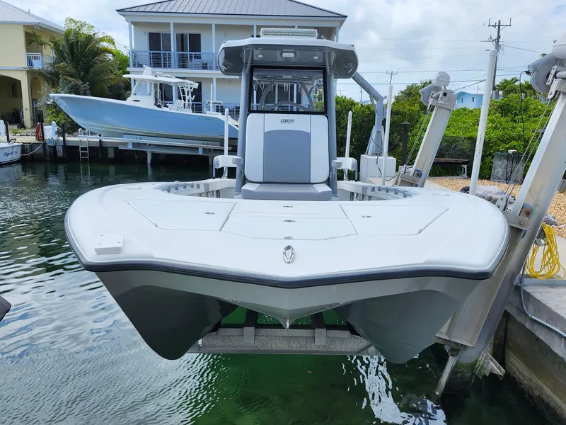Slide: The Image of 2022 Costa Custom Boats 264 HC on lift, docked in a marina setting. - 2