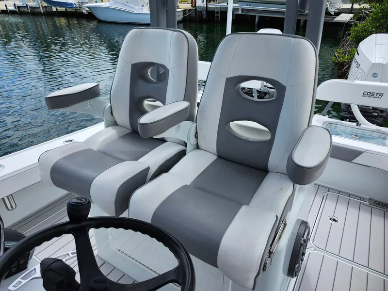 Slide: The Image of 2022 Costa Custom Boats 264 HC with dual gray and white captain's chairs by the water. - 20