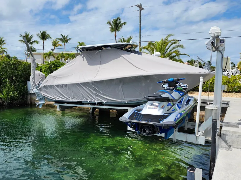 Slide: The Image of Covered 2022 Costa Custom Boats 264 HC and jet ski on lift by tropical waterfront. - 27