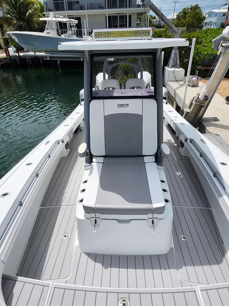 Slide: The Image of 2022 Costa Custom Boats 264 HC, sleek design, spacious deck, docked by waterfront homes. - 8