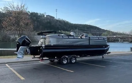 Slide: The Image of 2024 Regency 250 LE3 pontoon boat parked near a scenic waterfront. - 2