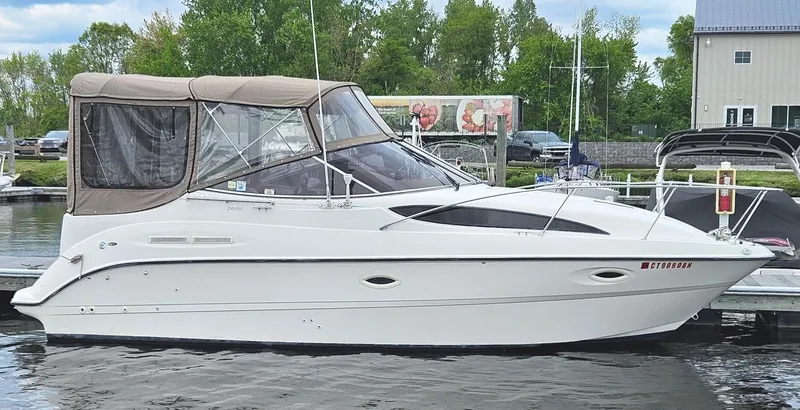 Slide: The Image of 2001 Bayliner 2655 Cierra boat docked at a marina with trees in the background. - 0