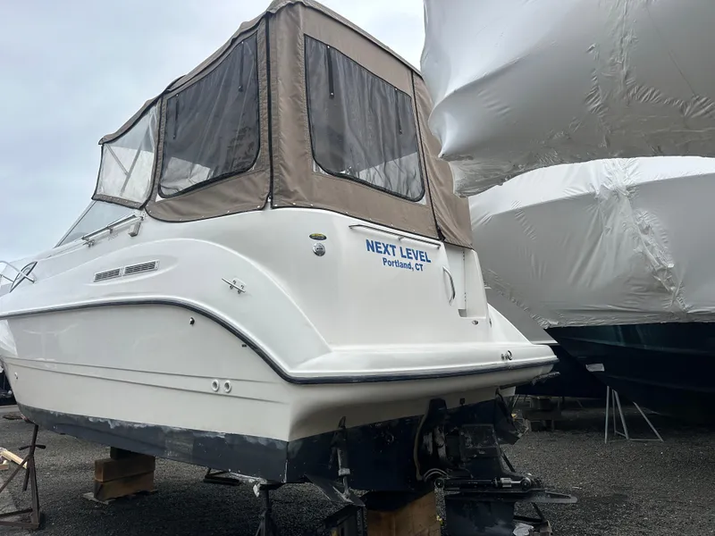 Slide: The Image of 2001 Bayliner 2655 Cierra boat with tan canopy, named "Next Level," on dry dock. - 5