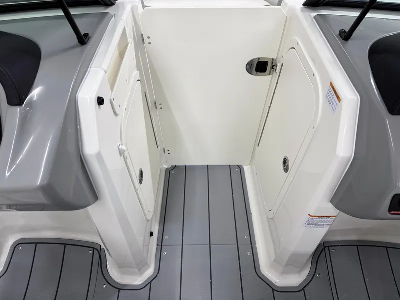 Slide: The Image of 2025 Chaparral 23 SSi boat interior with gray flooring and white storage compartments. - 26