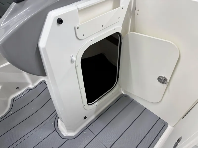 Slide: The Image of 2025 Chaparral 23 SSi boat storage compartment with open hatch and gray flooring. - 28
