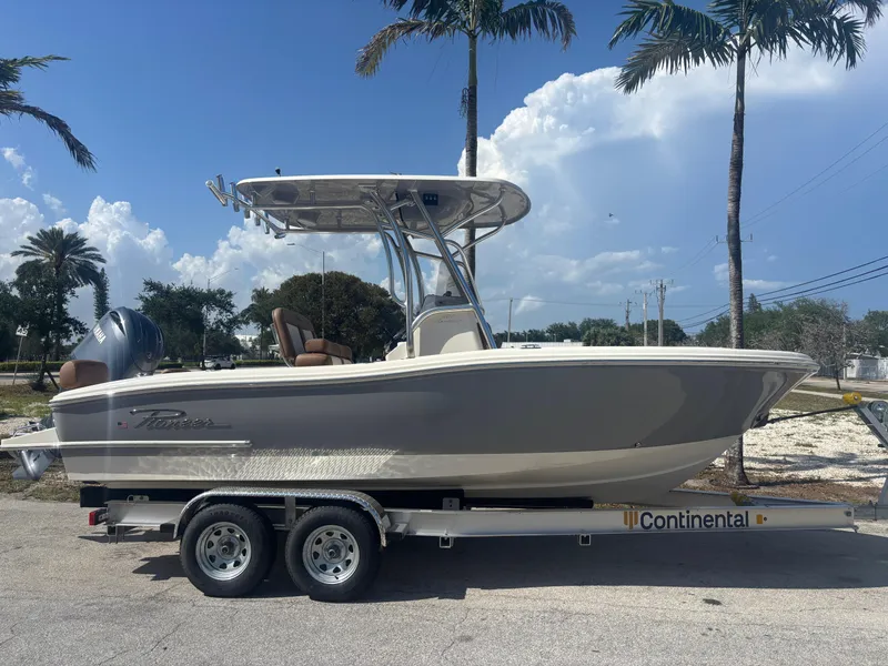 Slide: The Image of 2025 Pioneer 202 Sportfish boat on trailer, parked under palm trees, clear sky background. - 0