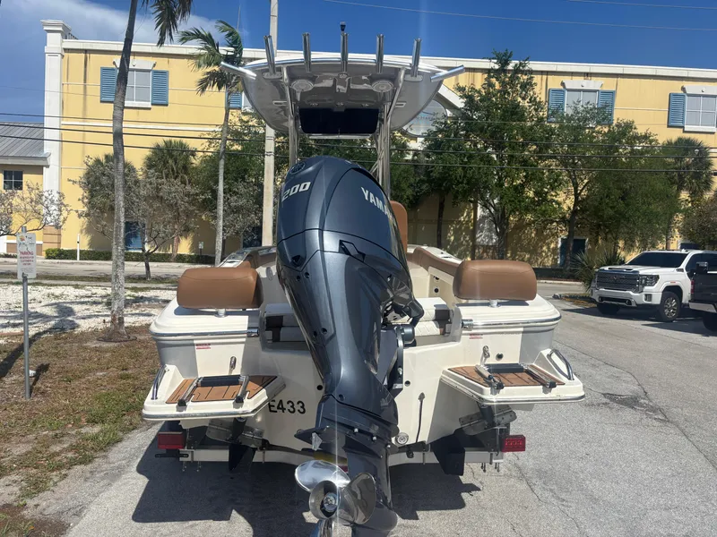 Slide: The Image of 2025 Pioneer 202 Sportfish boat with Yamaha engine, parked outdoors on a sunny day. - 2