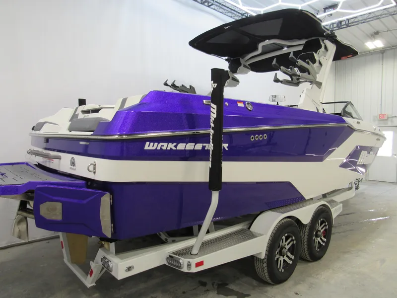 Slide: The Image of 2025 Malibu Wakesetter 24 MXZ boat in vibrant purple on a trailer, indoors. - 3