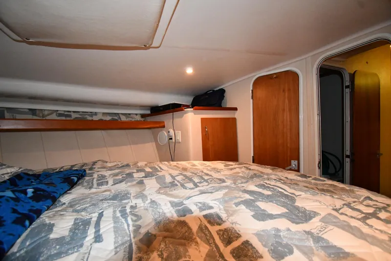 Slide: The Image of 1997 Mainship 40 Sedan Bridge cabin interior with bed, wooden cabinets, and soft lighting. - 27