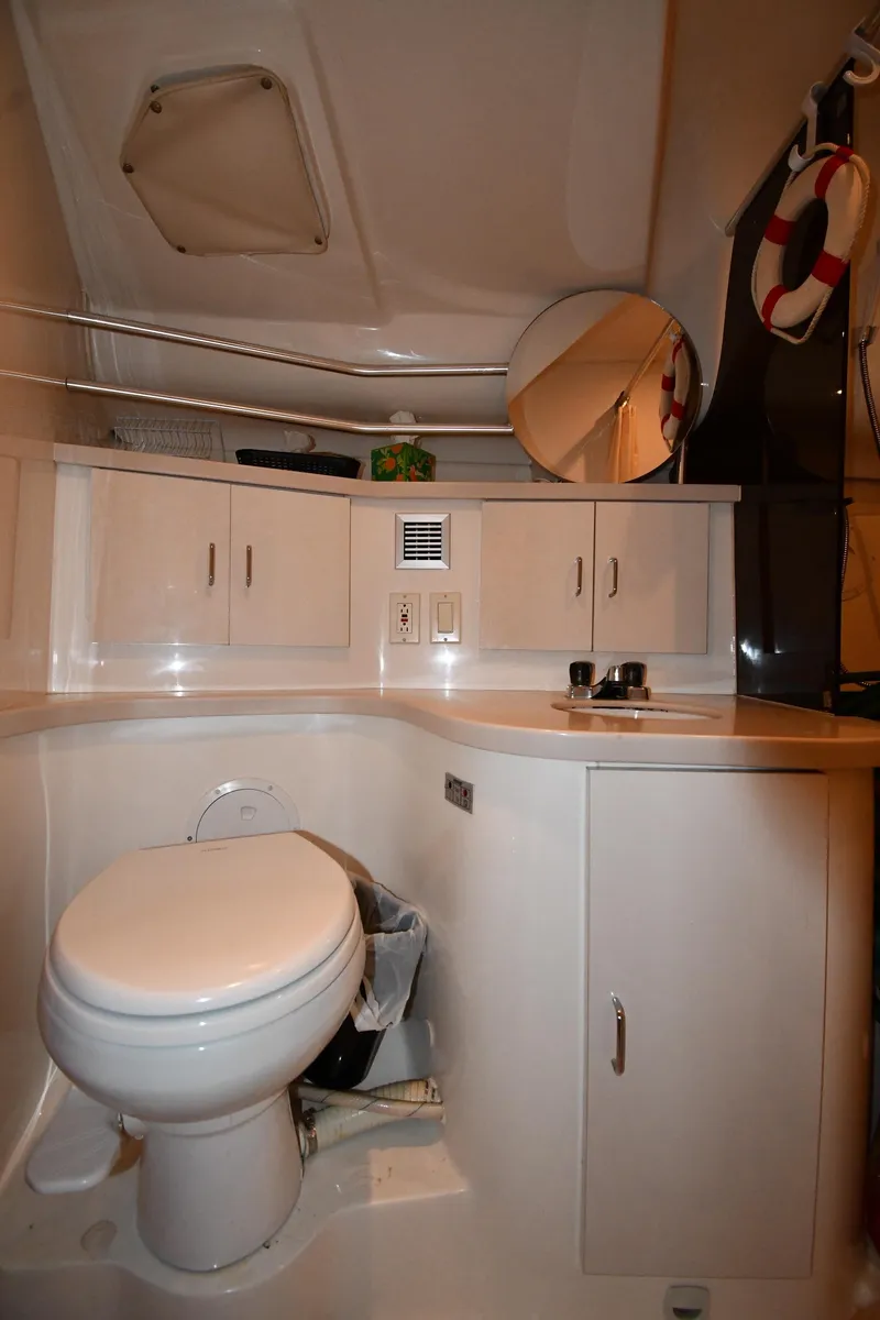 Slide: The Image of 1997 Mainship 40 Sedan Bridge bathroom with white cabinetry and round mirror. - 31