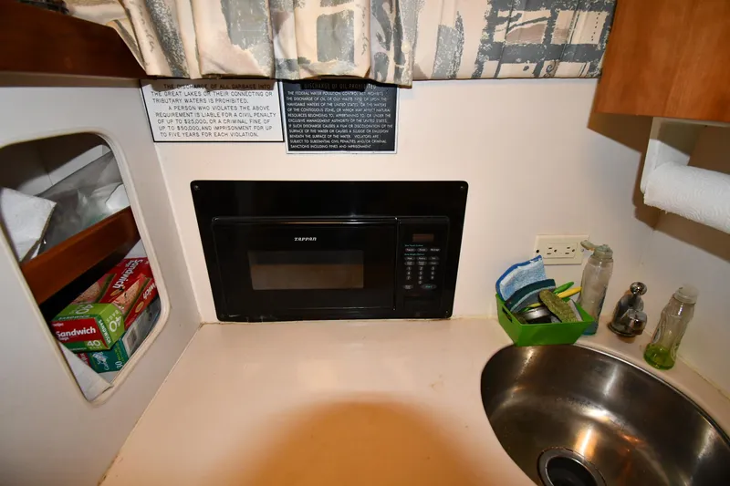 Slide: The Image of 1997 Mainship 40 Sedan Bridge kitchen with microwave, sink, and storage shelves. - 43