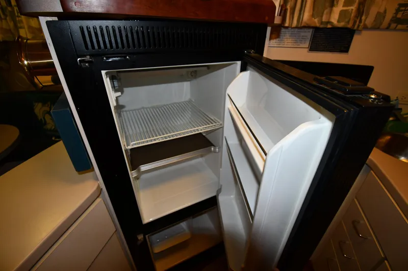 Slide: The Image of Open refrigerator inside 1997 Mainship 40 Sedan Bridge yacht, showing empty shelves and door compartments. - 44
