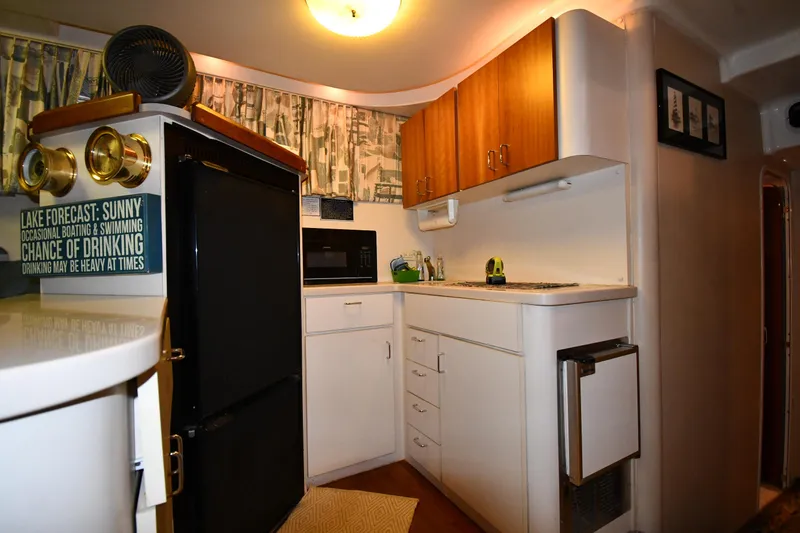 Slide: The Image of 1997 Mainship 40 Sedan Bridge kitchen with fridge, microwave, and wooden cabinets. - 49