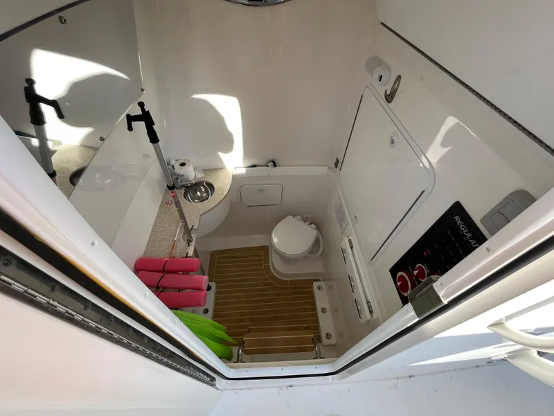 Slide: The Image of 2018 Regulator 31 boat interior with compact bathroom and wooden flooring. - 21