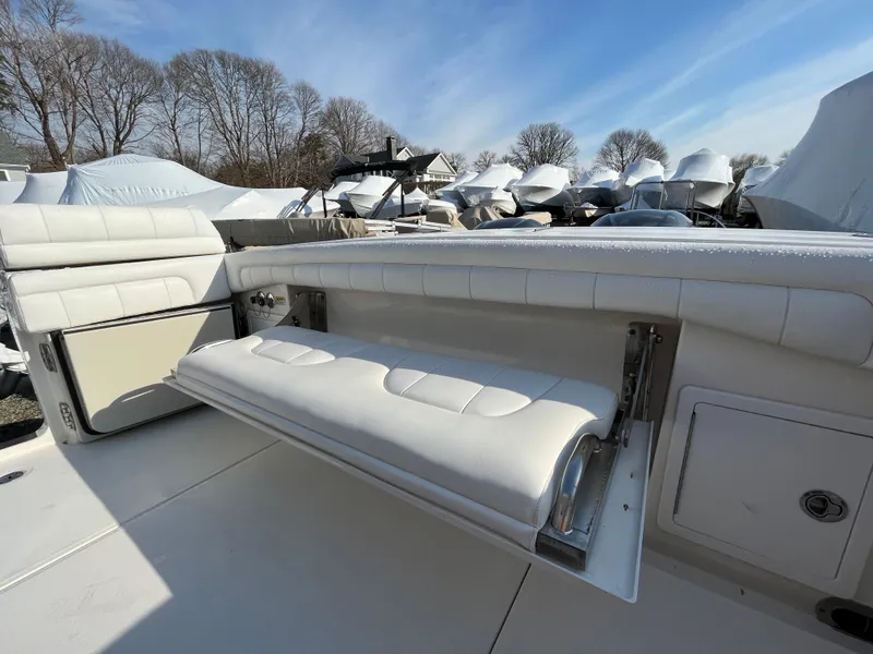 Slide: The Image of 2018 Regulator 31 boat with white cushioned seating, outdoor storage, and clear blue sky. - 28