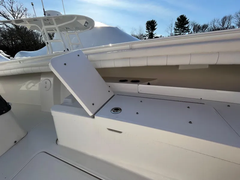 Slide: The Image of 2018 Regulator 31 boat interior with open storage compartment, white seating, and clear sky. - 42