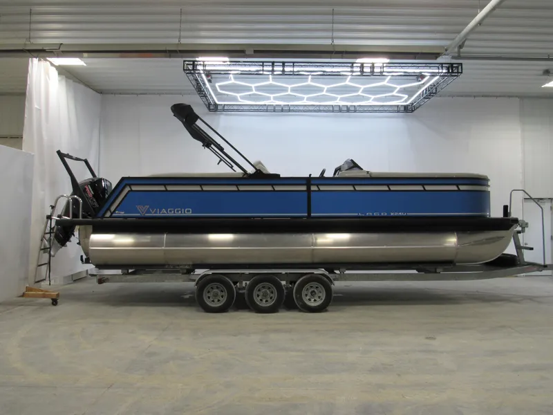 Slide: The Image of 2025 Viaggio X24U pontoon boat in a showroom, featuring a sleek blue design. - 0