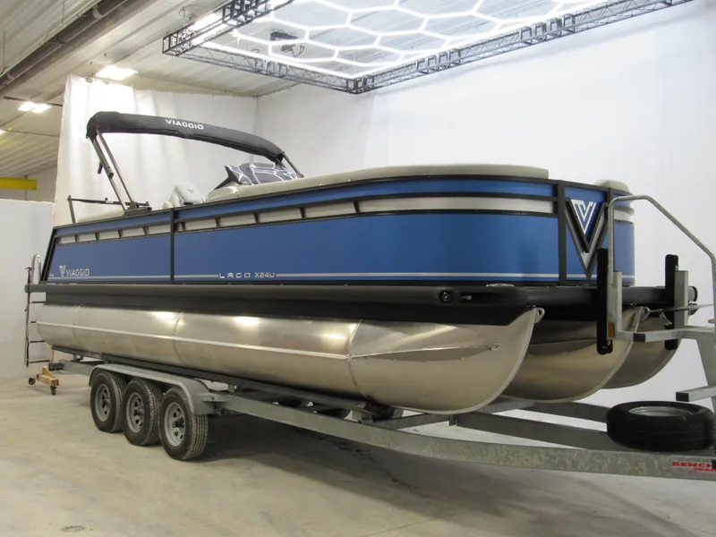 Slide: The Image of 2025 Viaggio X24U pontoon boat on trailer in indoor showroom. - 2