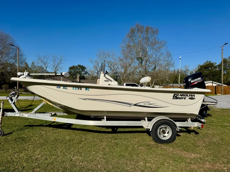 Slide: The Image of 2014 Carolina Skiff 198 DLV boat on trailer, parked on grass, clear sky background. - 1