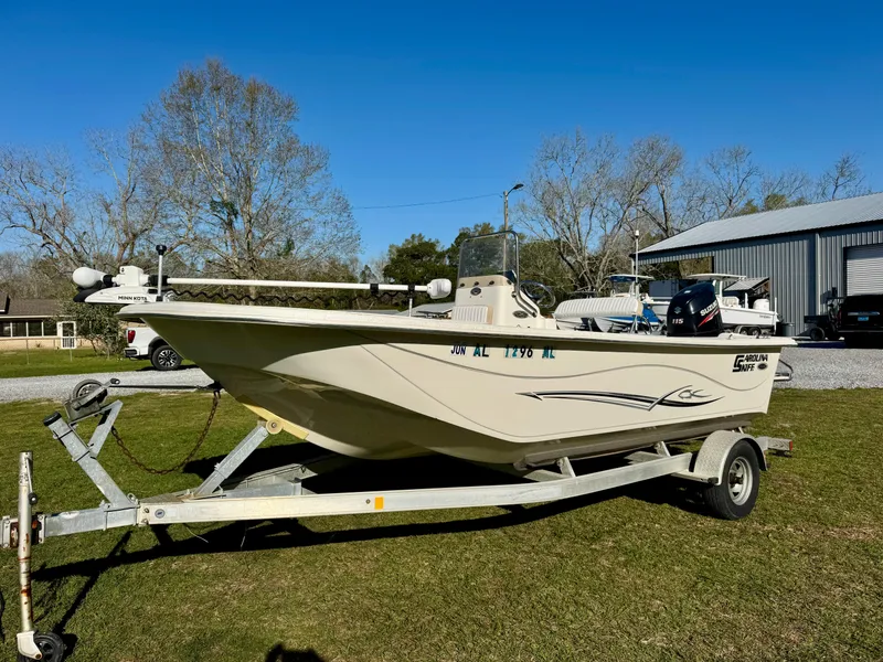 Slide: The Image of 2014 Carolina Skiff 198 DLV boat on trailer, parked on grass under clear blue sky. - 2