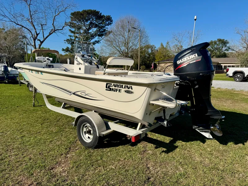 Slide: The Image of 2014 Carolina Skiff 198 DLV boat on trailer with Suzuki outboard motor, parked on grass. - 3