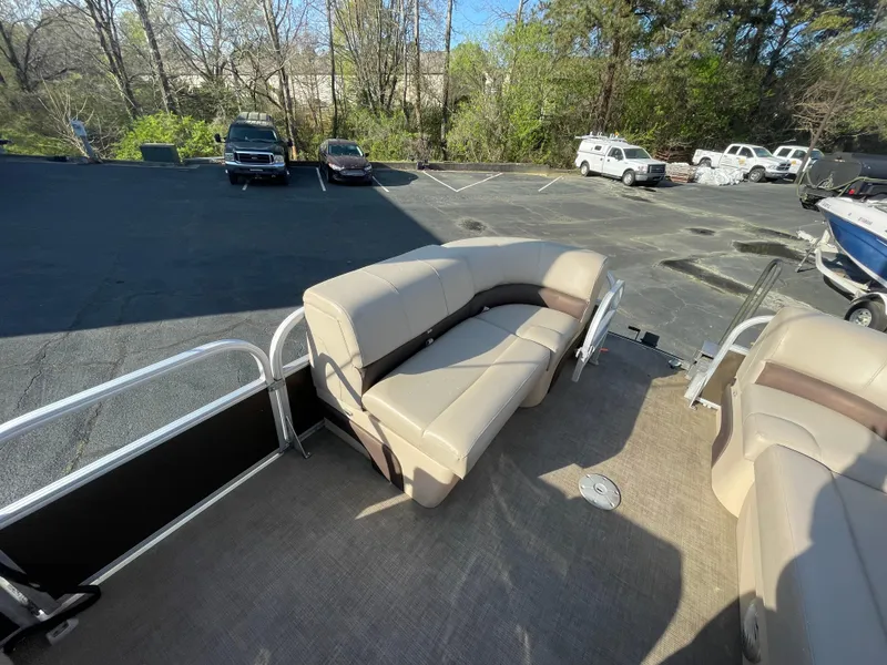Slide: The Image of 2019 Sun Tracker SportFish 22 DLX pontoon boat with beige seating in a parking lot. - 25