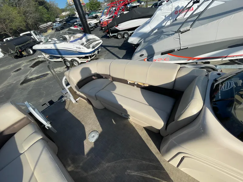 Slide: The Image of 2019 Sun Tracker SportFish 22 DLX pontoon boat interior with beige seating, parked among other boats. - 26