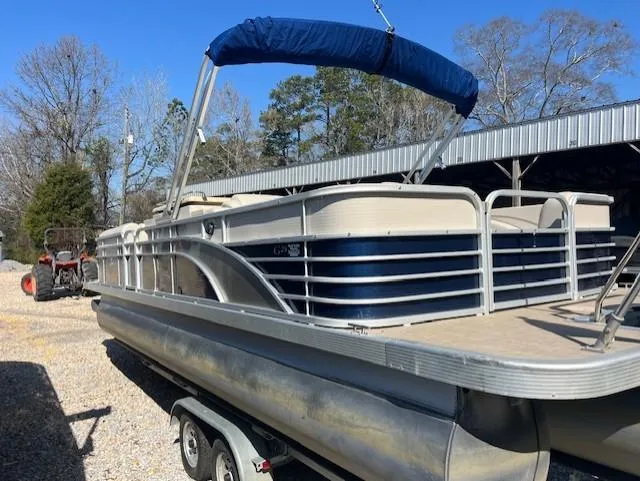 Slide: The Image of 2015 Bennington 2574 GCW pontoon boat on trailer, blue canopy, parked outdoors. - 4