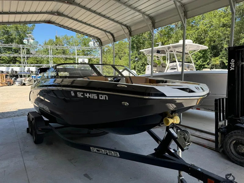 The Image of 2021 Scarab 215 ID boat on trailer in covered storage area. - 1