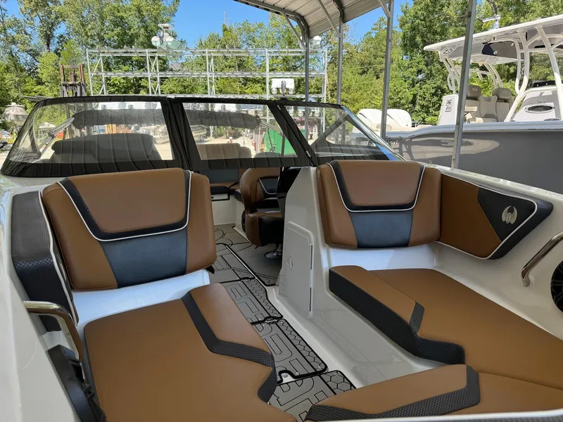Slide: The Image of 2021 Scarab 215 ID boat interior with brown and black seating, under a canopy. - 10