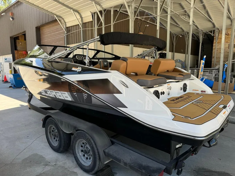Slide: The Image of 2021 Scarab 215 ID boat on trailer, sleek design, black and white exterior, tan seating. - 4