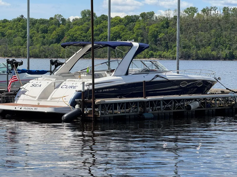 Slide: The Image of 2011 Regal 3350 Cuddy boat docked on a calm lake with lush green trees. - 1