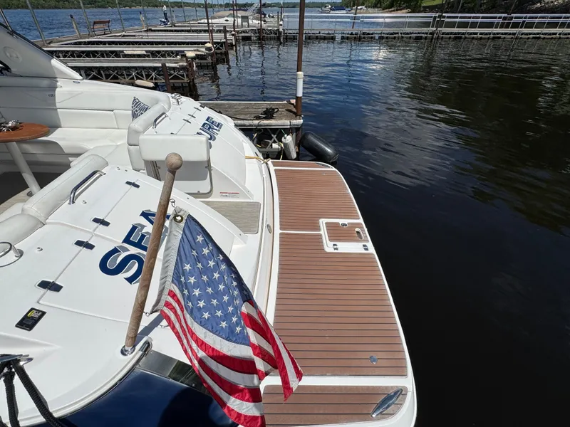 Slide: The Image of 2011 Regal 3350 Cuddy boat docked, featuring American flag and spacious deck. - 19