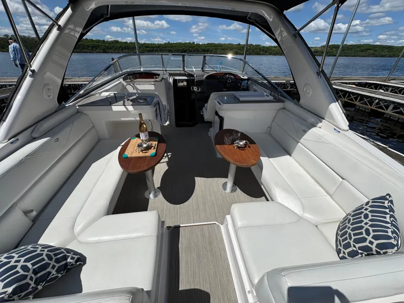 Slide: The Image of 2011 Regal 3350 Cuddy boat interior with white seating, wooden tables, and scenic lake view. - 22