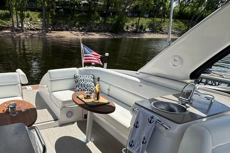 Slide: The Image of Luxurious 2011 Regal 3350 Cuddy boat interior with seating, table, and American flag by the water. - 24