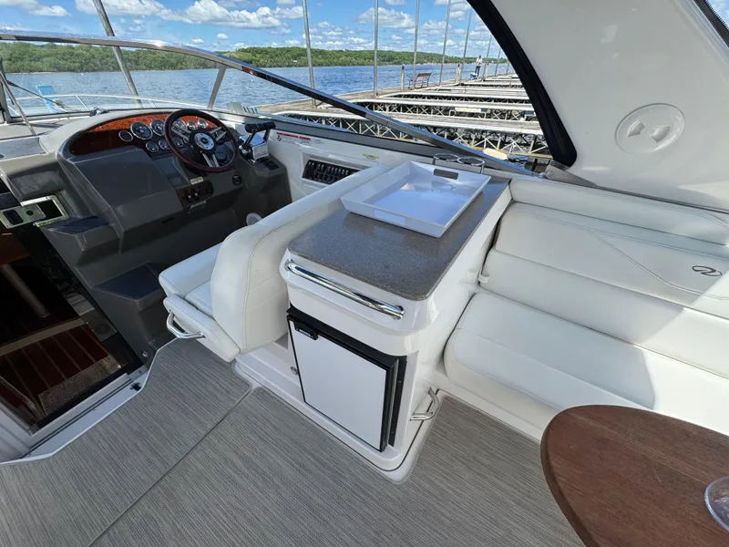 Slide: The Image of 2011 Regal 3350 Cuddy interior with seating, helm, and kitchenette on a sunny day. - 27