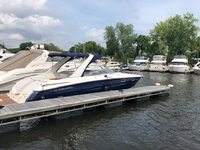 Slide: The Image of 2011 Regal 3350 Cuddy boat docked at a marina with other vessels. - 3