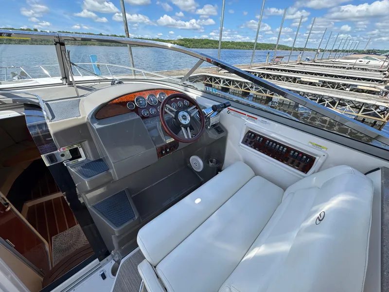 Slide: The Image of 2011 Regal 3350 Cuddy boat interior with steering wheel and dashboard, docked by the water. - 32