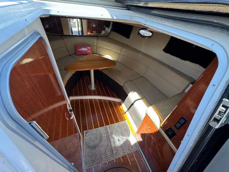 Slide: The Image of 2011 Regal 3350 Cuddy interior with wood flooring, beige seating, and a small table. - 35