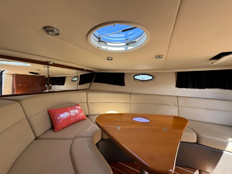 Slide: The Image of 2011 Regal 3350 Cuddy interior with beige seating, wooden table, and circular skylight. - 38