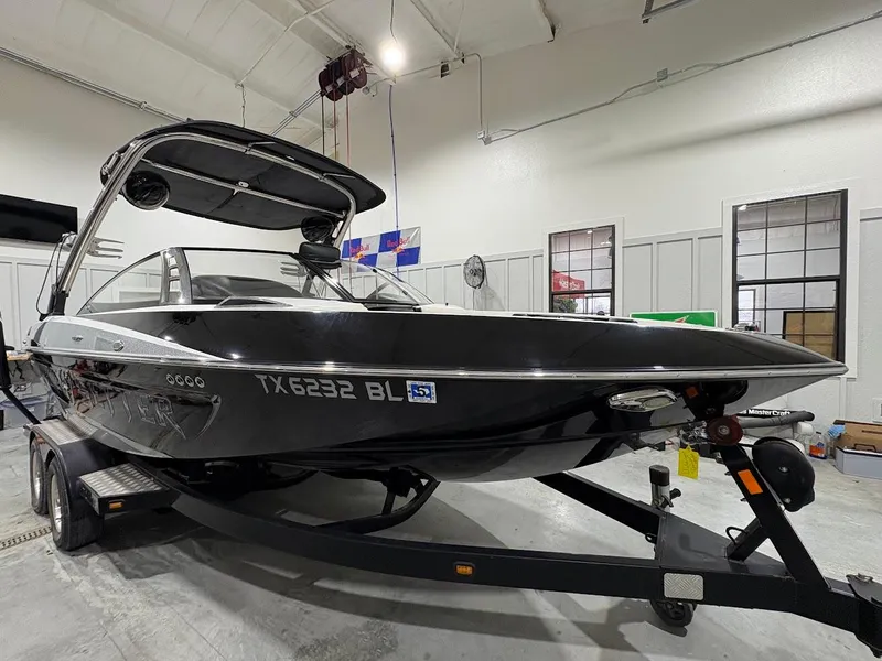 Slide: The Image of 2011 Malibu Wakesetter 21 VLX boat in a garage, sleek black design on trailer. - 5