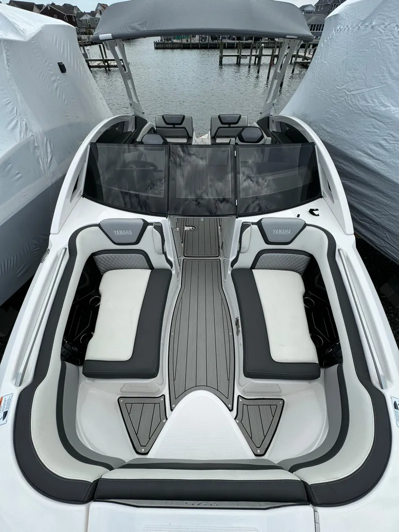Slide: The Image of 2021 Yamaha Boats 275SE with sleek seating and modern design, docked by the water. - 14