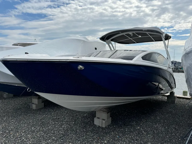 Slide: The Image of 2021 Yamaha Boats 275SE, blue hull, docked on gravel, under cloudy sky. - 3