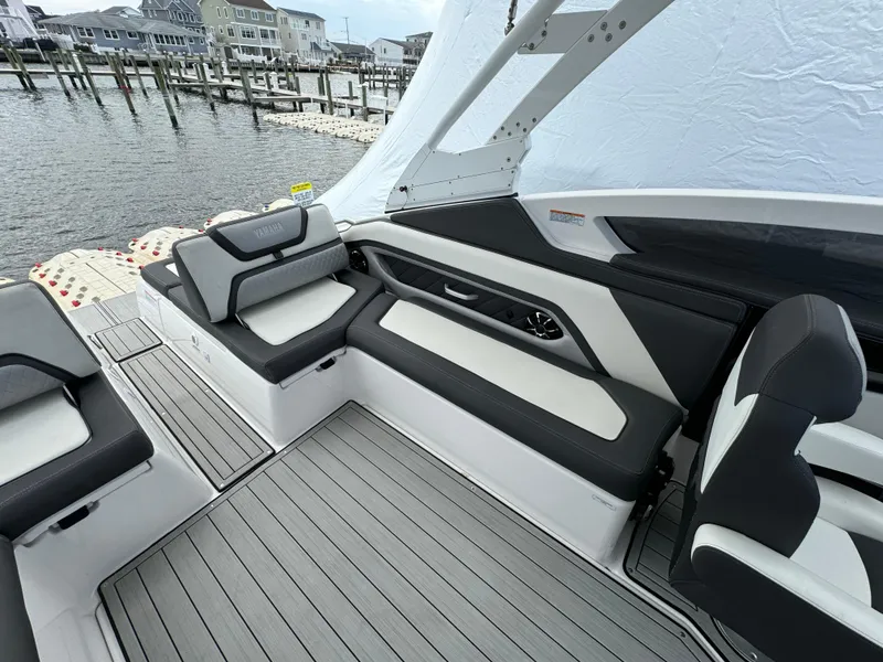 Slide: The Image of 2021 Yamaha Boats 275SE interior with sleek seating and modern design at a marina. - 8